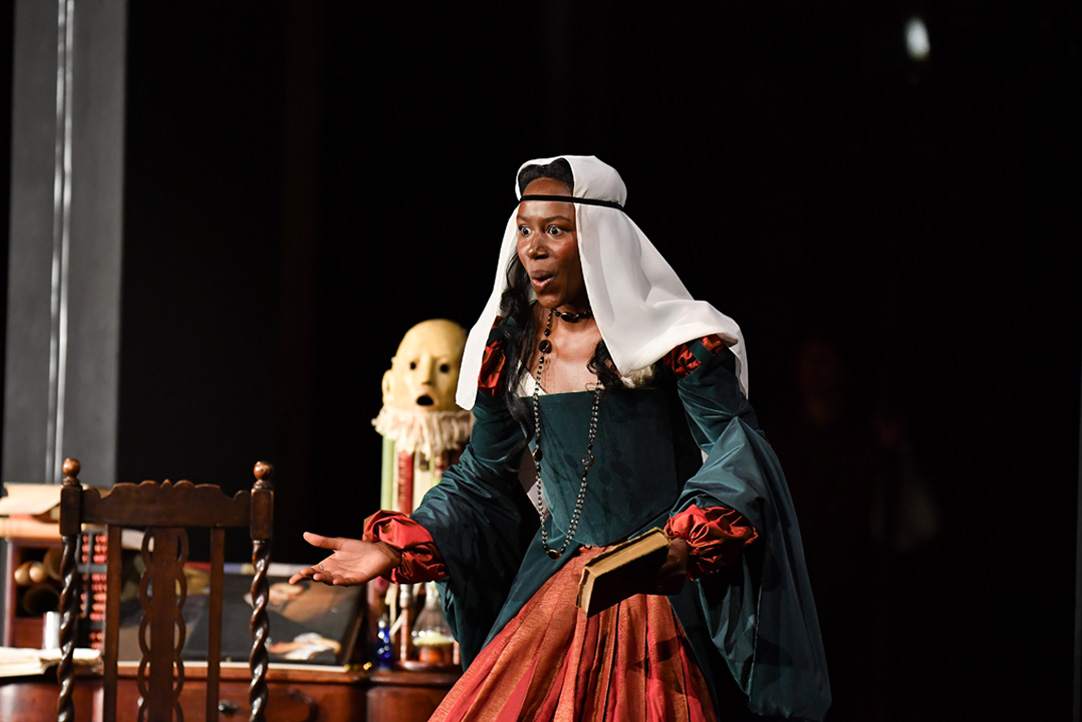 A women wearing a medieval historical costume, singing on stage.